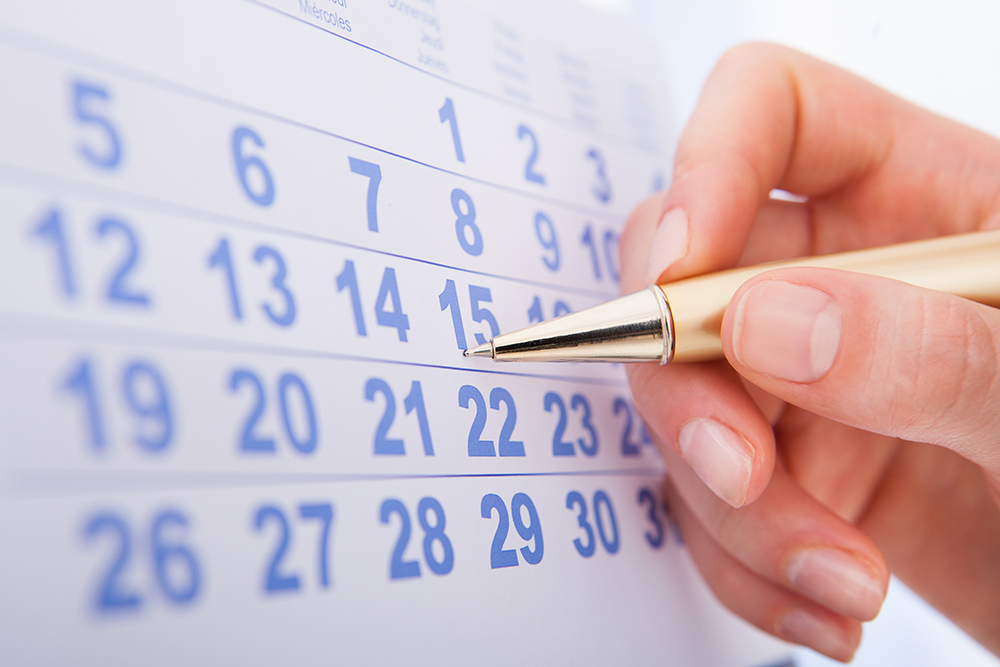 Person using a pen to mark on a calendar