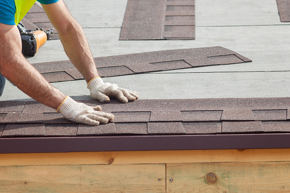 Roofer installing new shingles after home inspection services 